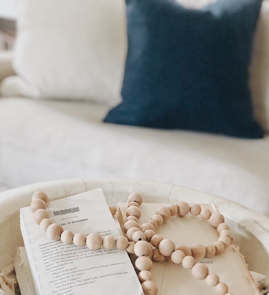 Taking the covers off of unwanted books and placing them in an oversized wooden bowl is an easy centerpiece. Complete the layered look by adding a wooden bead garland. This DIY garland is simple, you can read more about how to make it here .