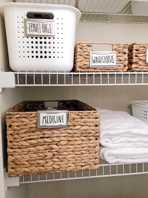 How To Create Organize Your Bathroom Closet, tips featured by top AL home blogger, She Gave It A Go | How to Organize a Bathroom Closet by popular Alabama lifestyle blog, She Gave It A Go: image of a bathroom closet organized with woven seagrass basket and white plastic bins. 