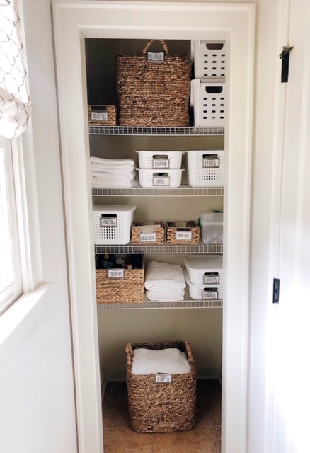 How To Create Organize Your Bathroom Closet, tips featured by top AL home blogger, She Gave It A Go | How to Organize a Bathroom Closet by popular Alabama lifestyle blog, She Gave It A Go: image of a bathroom closet organized with white plastic basket and woven seagrass baskets. 