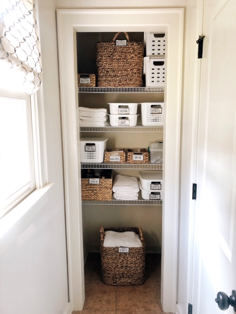 How To Create Organize Your Bathroom Closet, tips featured by top AL home blogger, She Gave It A Go | How to Organize a Bathroom Closet by popular Alabama lifestyle blog, She Gave It A Go: image of a bathroom closed organized with white plastic and seagrass baskets. 