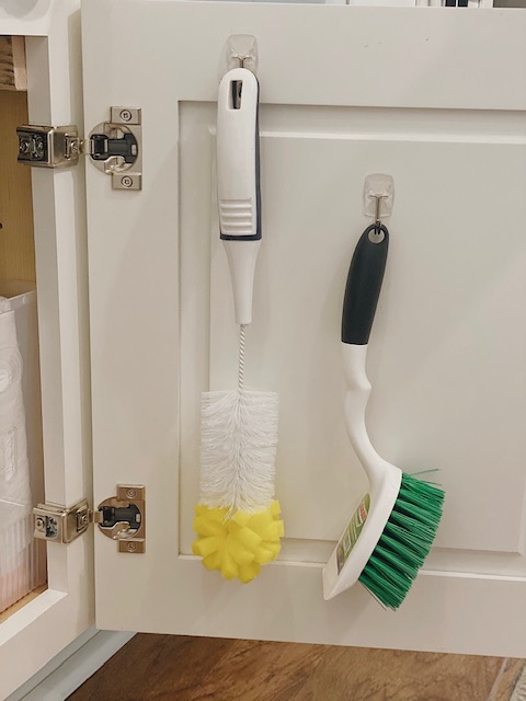 5 Easy and Super Practical Under Sink Organization Ideas for your Home featured by top AL home and lifestyle blogger, She Gave It A Go |Under Sink Organization by popular Alabama lifestyle blog, She Gave It A Go: image of cleaning brushes hanging on hooks on a cabinet door. 