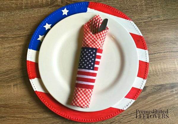 DIY Memorial Day Table Decorations featured by top AL home and lifestyle blogger, She Gave It A Go |Memorial Day Table Top Decorations by popular Alabama DIY blog, She Gave It A Go: image of an American flag plate charger, white plate, and red and white checked napkin wrapped around a sliver fork and knife. 