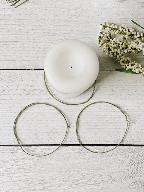 Cool DIY Summer Candle Rings, a Tutorial featured by top AL home blogger, She Gave It A Go | Candle Rings by popular Alabama DIY blog, She Gave It A Go: image of a white pillar candle in the center of a floral wire ring next to two other floral wire rings. 