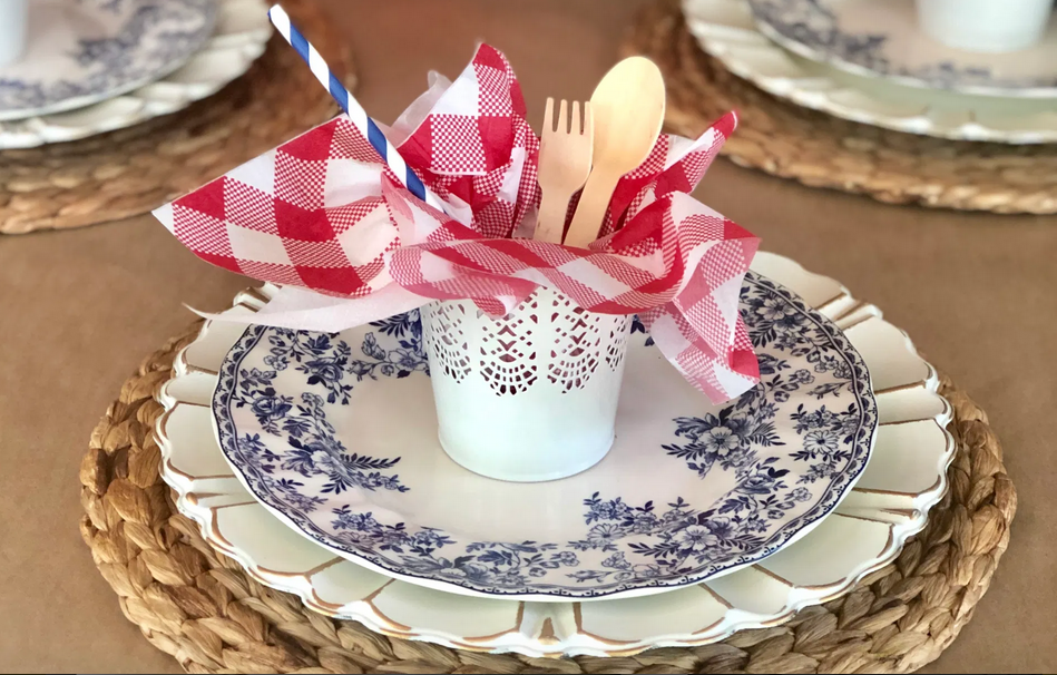 DIY Memorial Day Table Decorations featured by top AL home and lifestyle blogger, She Gave It A Go |Memorial Day Table Top Decorations by popular Alabama DIY blog, She Gave It A Go: image of sea grass charger, white plate, blue and white plate and white metal planter filled with a red and white checker napkin, blue and white stripe straw, and wooden fork and spoon. 