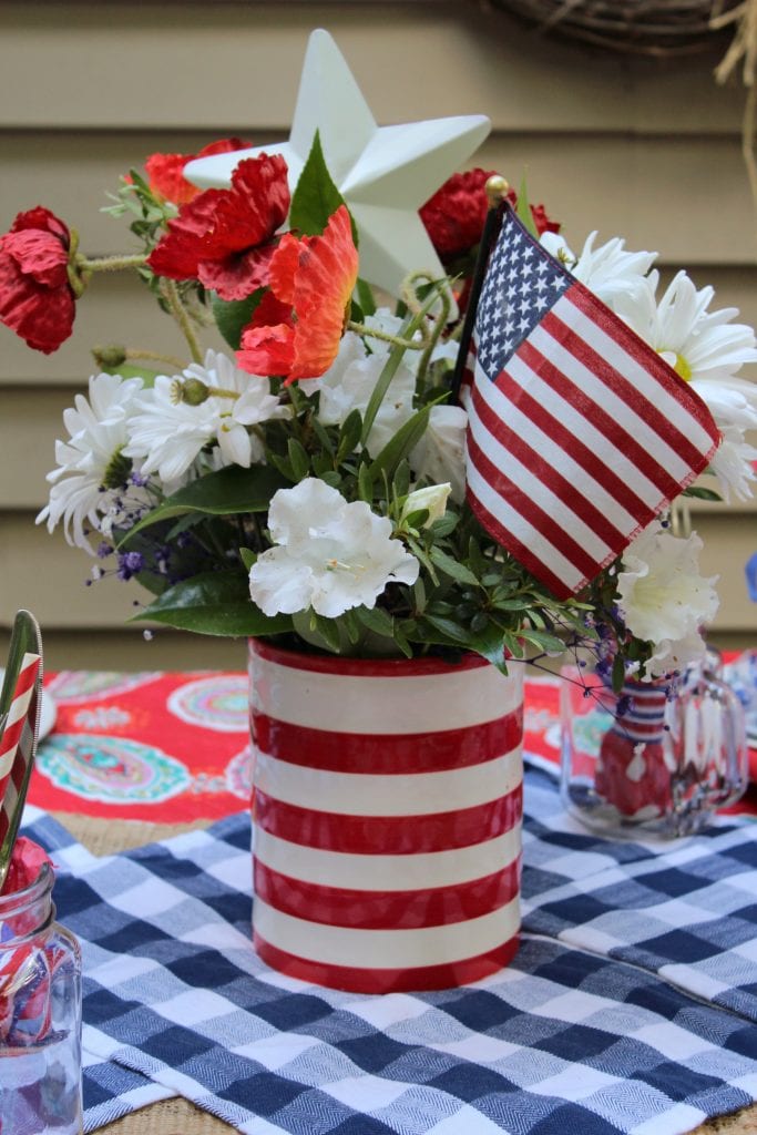 DIY Memorial Day Table Decorations featured by top AL home and lifestyle blogger, She Gave It A Go |Memorial Day Table Top Decorations by popular Alabama DIY blog, She Gave It A Go: image of a red and white stripe vase filled with faux white and red flowers, white metal star, and mini American flag.