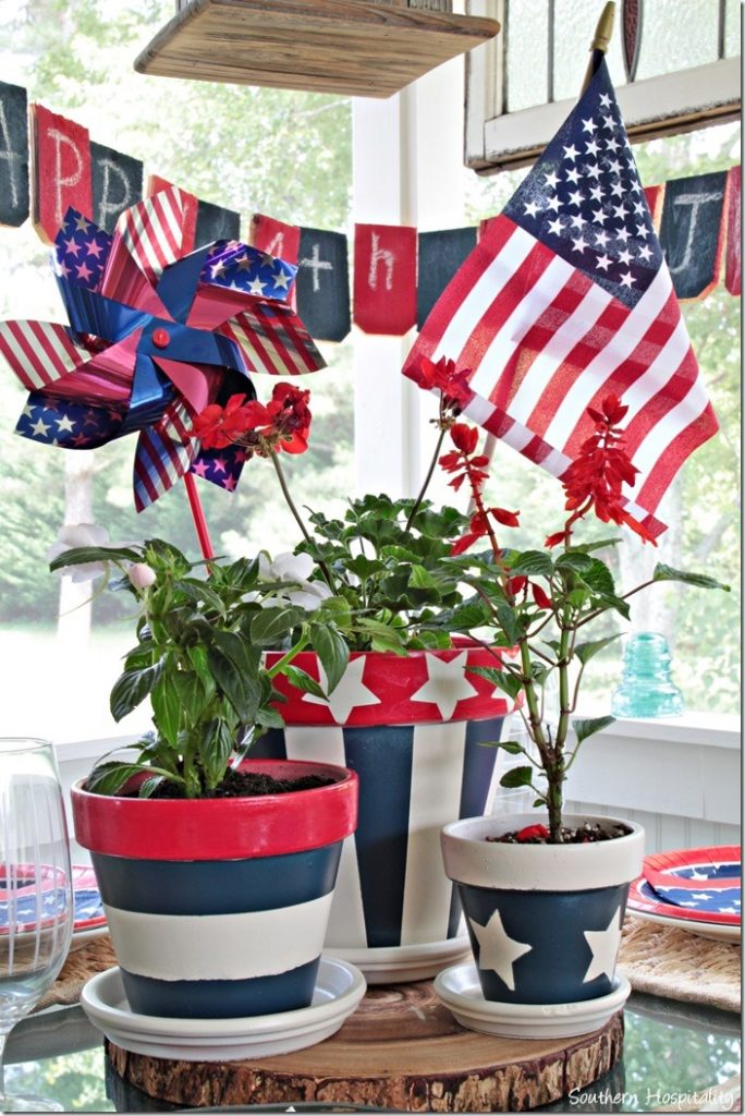 DIY Memorial Day Table Decorations featured by top AL home and lifestyle blogger, She Gave It A Go |Memorial Day Table Top Decorations by popular Alabama DIY blog, She Gave It A Go: image of red white and blue planters filled with green plants, stars and stripes pinwheel, and a mini American flag. 