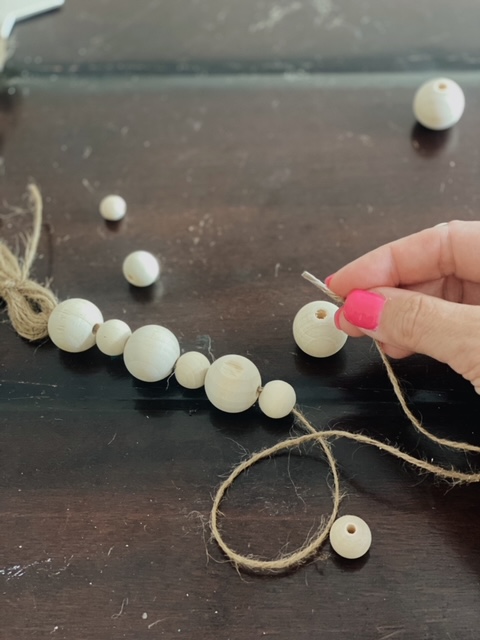 DIY Beaded Garland Tutorial, a summer craft featured by top AL DIY blogger, She Gave It A Go | DIY Beaded Garland by popular Alabama DIY blog, She Gave It A Go: image of a woman making a wooden bead garland. 