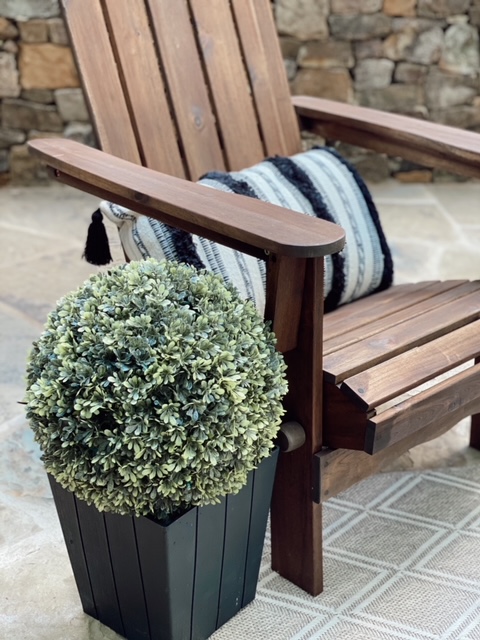 Family Patio Ideas for summer featured by top AL home blogger, She Gave It A Go |  Family Patio Ideas by popular Alabama life and style blog, She Gave It A Go: image of a wooden chair with a black and white tassel lumbar pillow next to a topper plant in a black planter. 