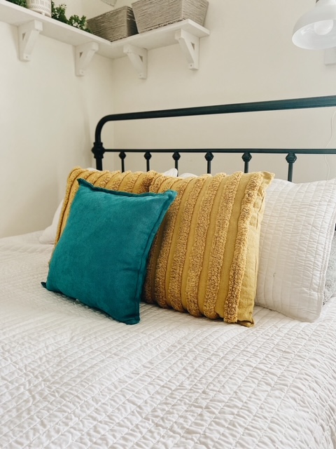 Teen Girl Bedroom Decor for Summer featured by top AL home blogger, She Gave It A Go | Teen Girl Bedroom by popular Alabama life and style blog, She Gave It A Go: image of a bedroom with a black metal bedroom with white bedding and mustard yellow and teal blue throw pillows.