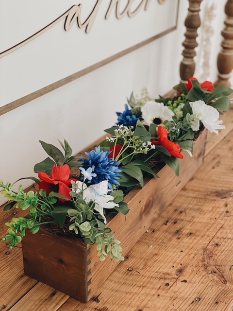 Patriotic Farmhouse Decor featured by top AL home blogger, She Gave It A Go | Patriotic Decor by popular Alabama life and style blog, She Gave It A Go: image of faux greenery and red, white, and blue flowers in a wooden planter box. 