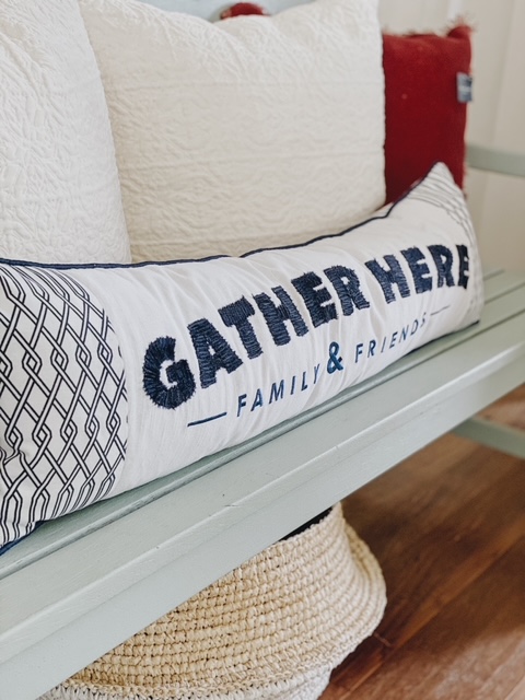 Patriotic Farmhouse Decor featured by top AL home blogger, She Gave It A Go | Patriotic Decor by popular Alabama life and style blog, She Gave It A Go: image of a blue and white gather here lumbar pillow on a grey bench with cream, white, and red throw pillows. 