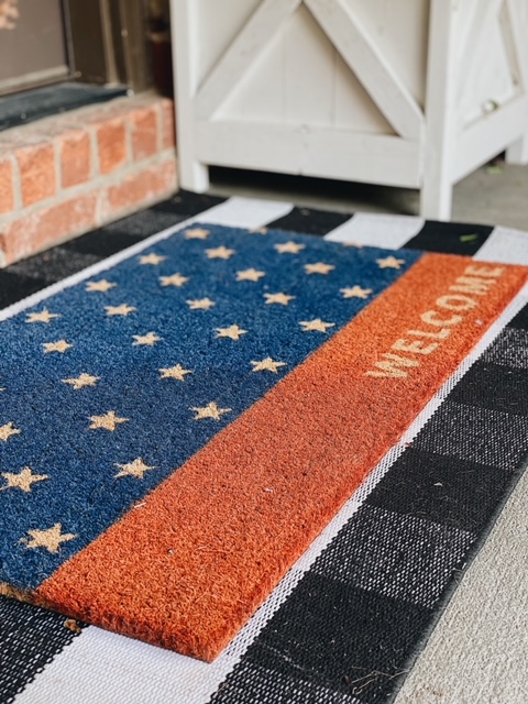 Patriotic Farmhouse Decor featured by top AL home blogger, She Gave It A Go | Patriotic Decor by popular Alabama life and style blog, She Gave It A Go: image of a American flag welcome mat on a black and white buffalo plat rug. 