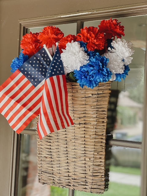 Patriotic Farmhouse Decor featured by top AL home blogger, She Gave It A Go | Patriotic Decor by popular Alabama life and style blog, She Gave It A Go: image of a woven basket filled with mini American flags and faux red, white, and blue flowers. 
