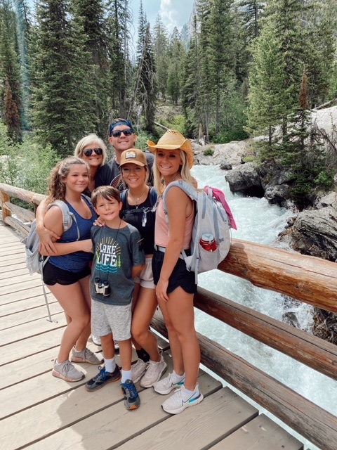 7 Best Things to Do in Jackson Hole with Teens featured by top AL family blogger, She Gave It A Go | Best Things to do in Jackson Hole by popular Alabama travel blog, She Gave it a Go: image of a family standing on a wooden bridge that goes across a river. 
