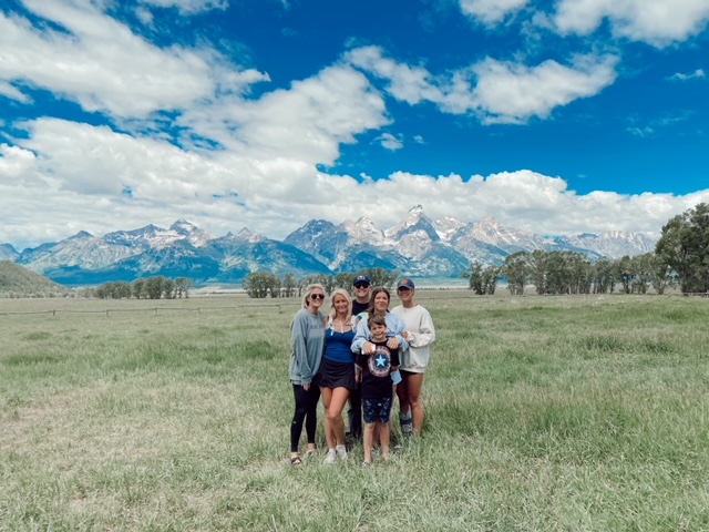 7 Best Things to Do in Jackson Hole with Teens featured by top AL family blogger, She Gave It A Go | Best Things to do in Jackson Hole by popular Alabama travel blog, She Gave it a Go: image of a family standing in a field with the Teton mountains in the background. 