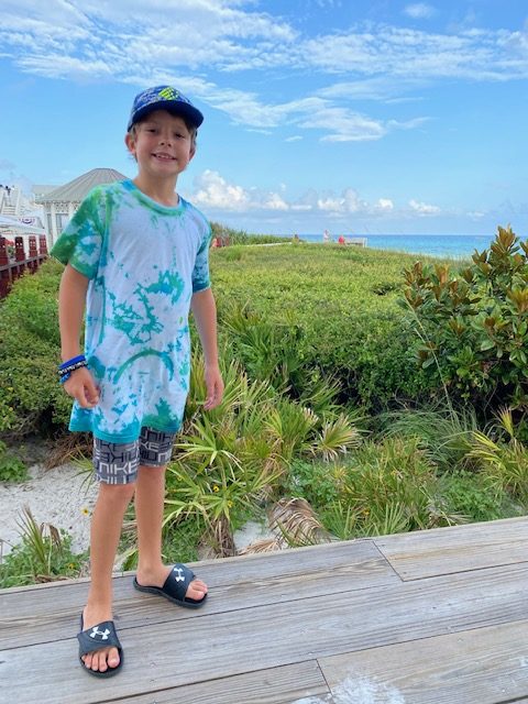 5 Essential Beach Vacation Tips for your Family featured by top AL family blogger, She Gave It a Go | Family Beach Vacation by popular Alabama travel blog, She Gave It A Go: image of a young boy standing outside on a wooden dock next to the ocean. 