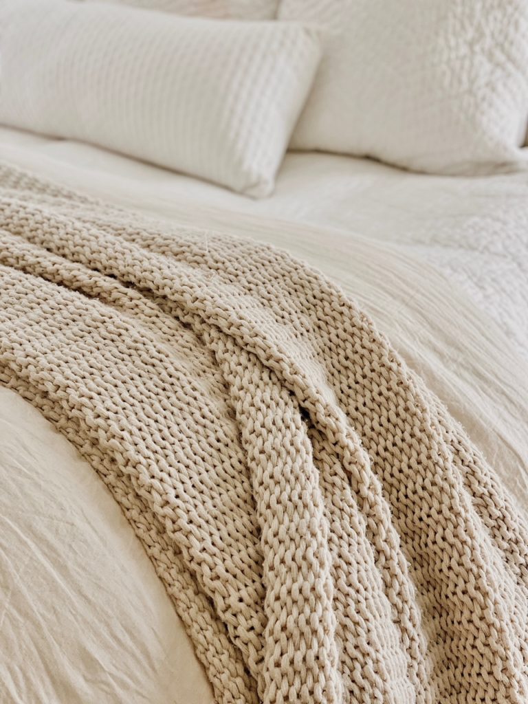 neutral master bed with cozy knit blanket