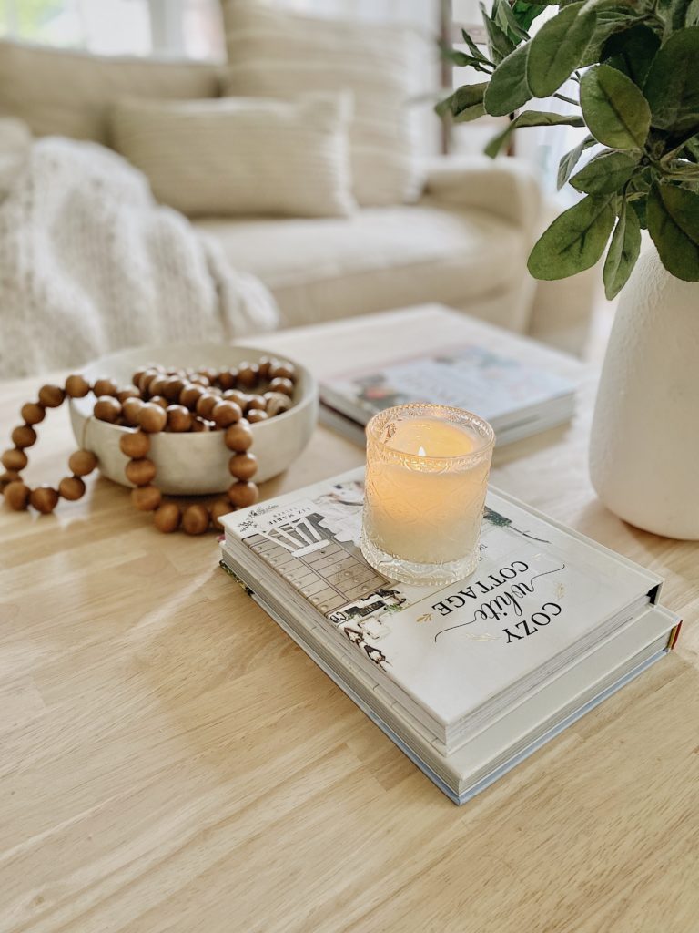 late summer decorating idea with wood beads in a bowl and summer scented candle on a coffee table