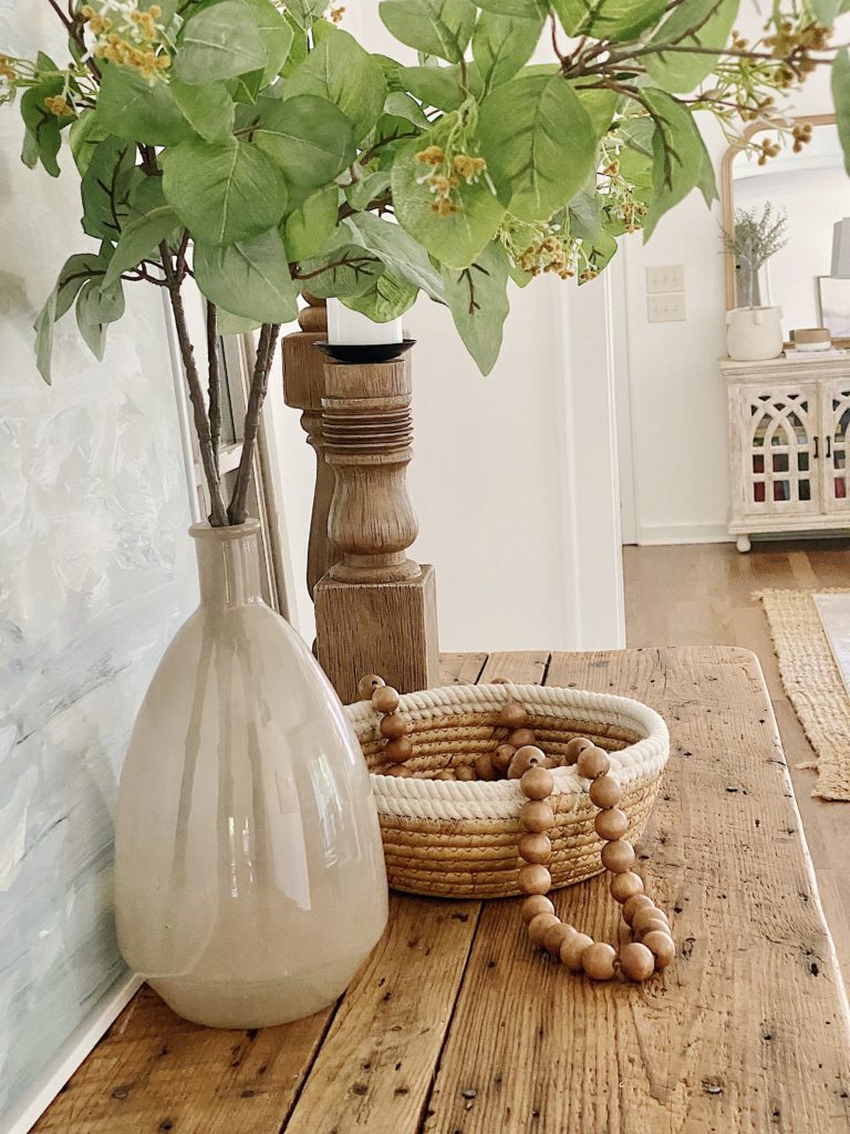 rustic console table with vase of greenery and woven rope basket
