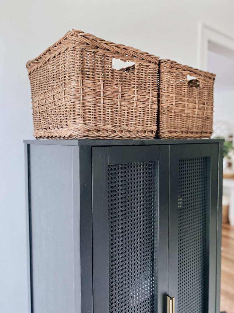 rattan baskets sitting on top of the black cabinet