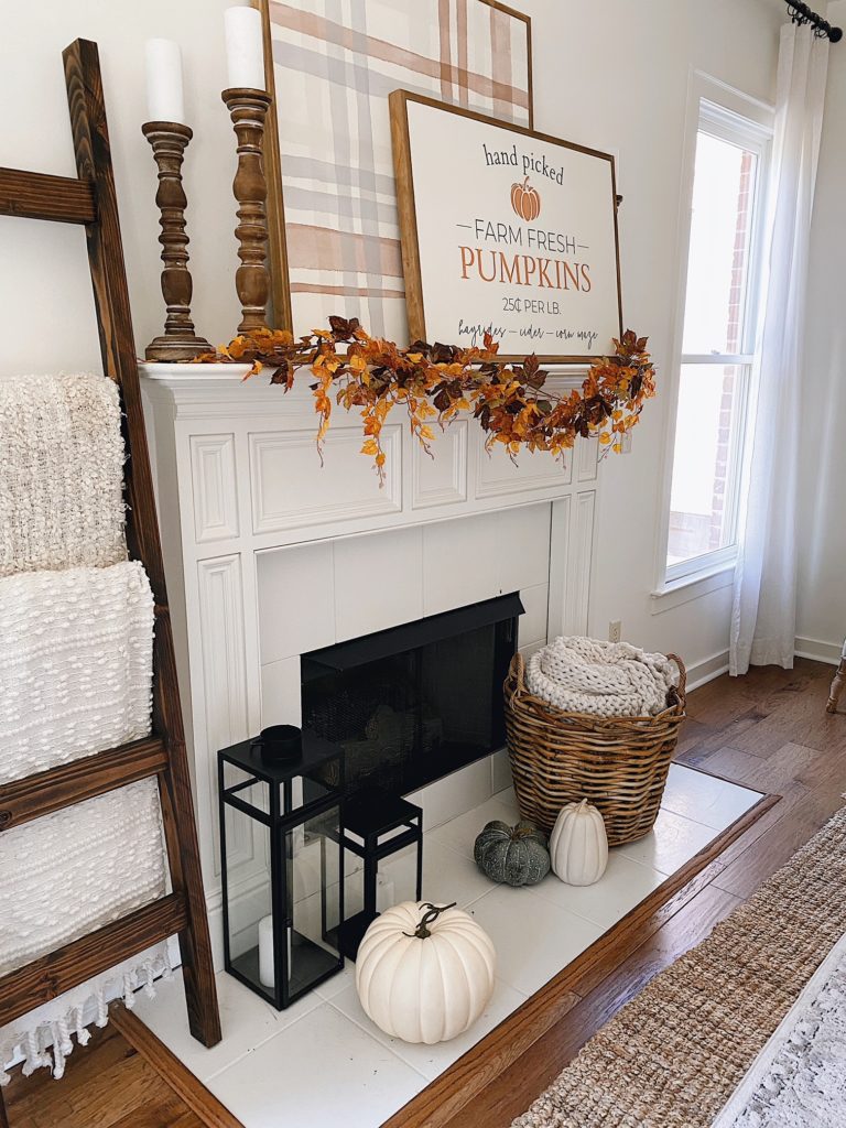 mantel decorated for fall with wood signs and a blanket ladder 