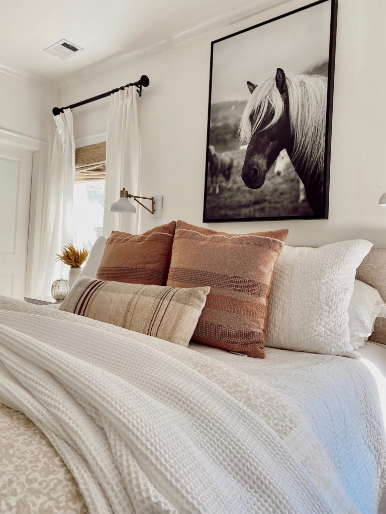 neutral bedding with rust colored throw pillows for fall