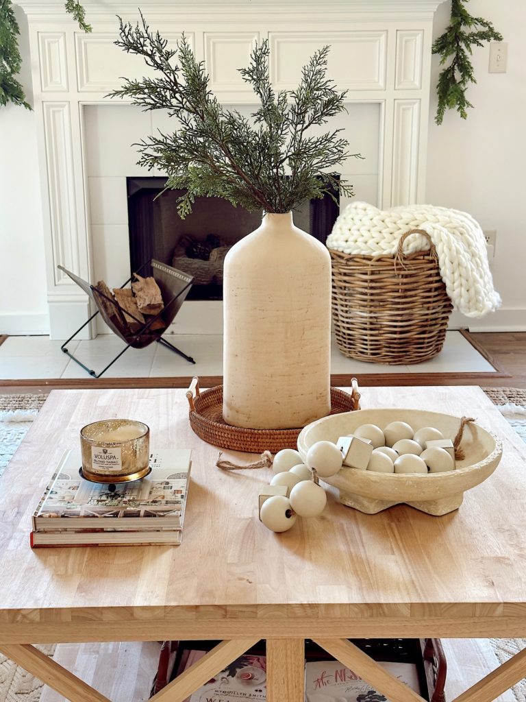 coffee table with a vase, books, candle, bowl and wood beads