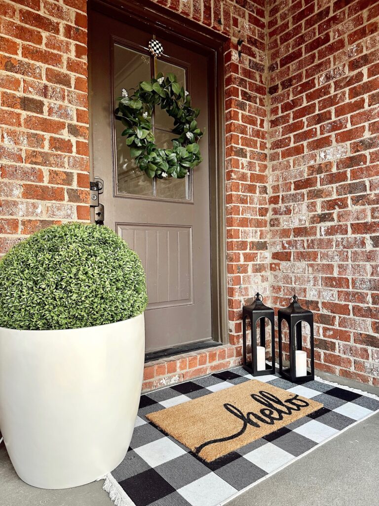 winter front door with black and white check rug and large planter 