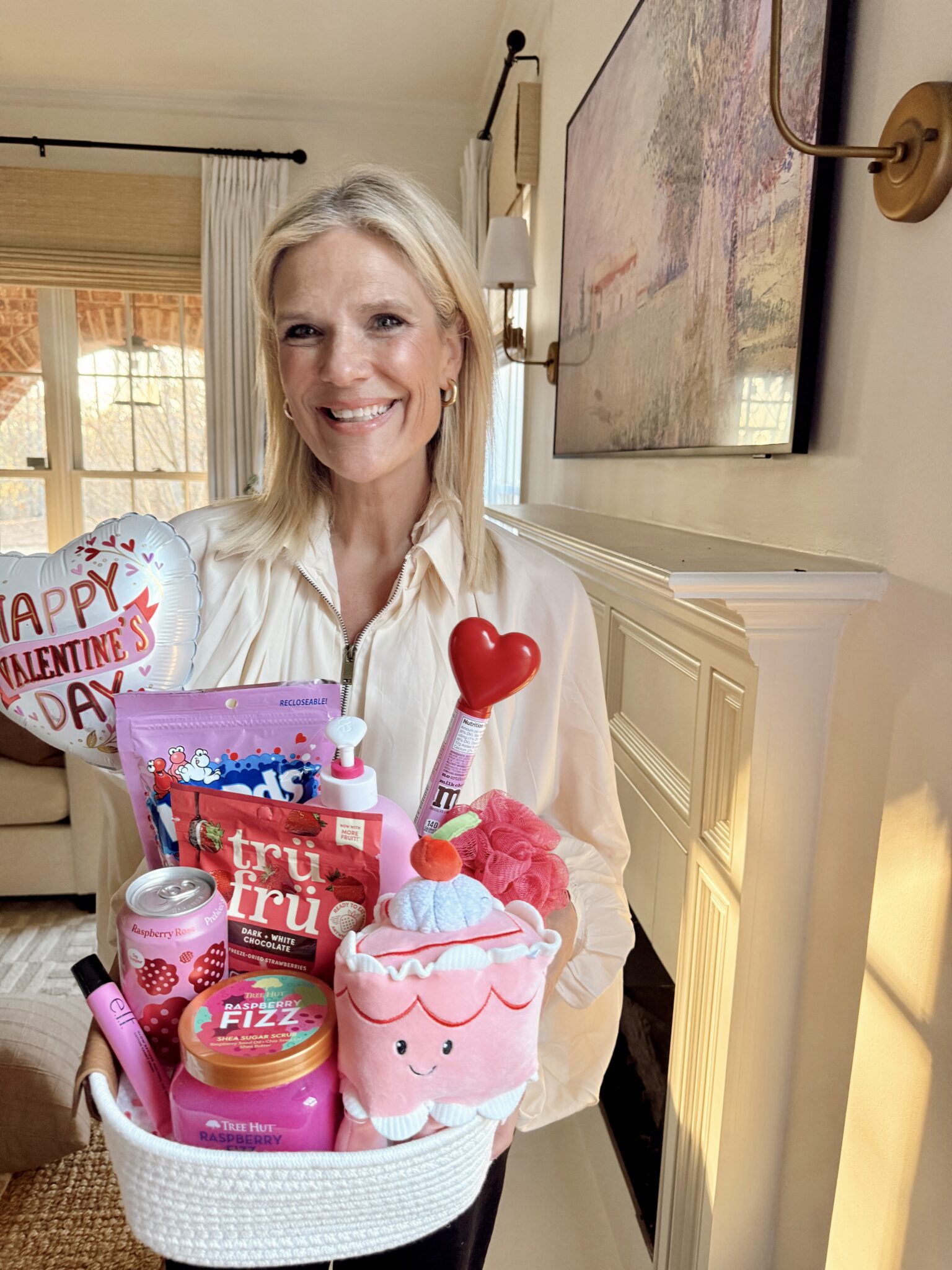 Brendt holding the Valentine gift basket full of self care items, snacks, and a cake plushie